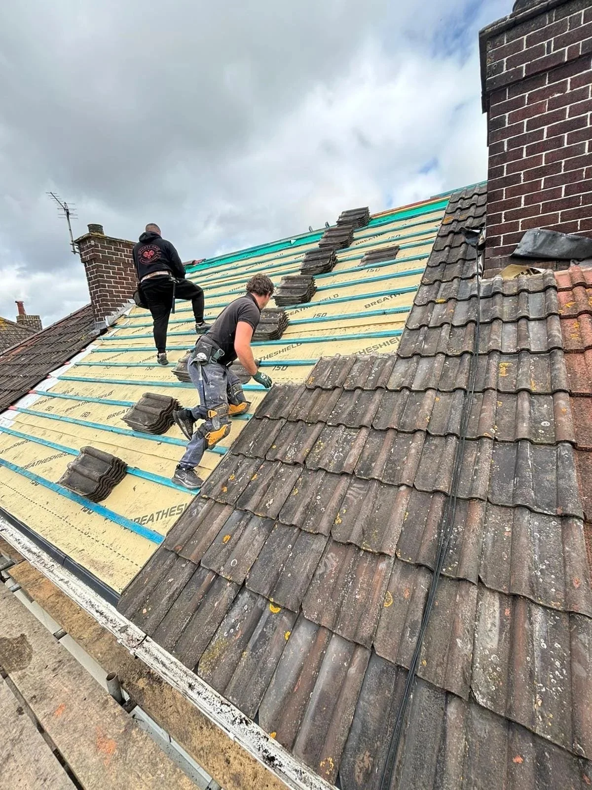 Roofers working with existing tiles during pitched-roof renewal